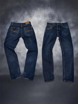 Nudie Jeans Big Bengt Dry Heavy Organic - Säljer ett par mörkblå jeans från Nudie Jeans, modell Big Bengt Dry Heavy Organic. Klassisk femficksdesign, raka ben och snygga kontrastsömmar. Tillverkade i 100% ekologisk bomull för en schysst känsla och hållbar stil.             .                                                                                                  Straight fit