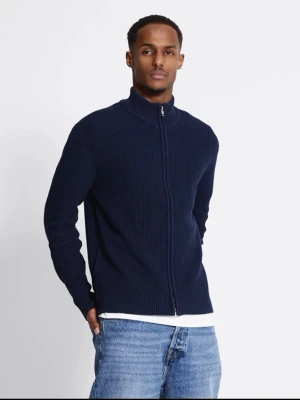 Mörkblå stickad kofta med dragkedja - Säljer en mörkblå stickad kofta med hel dragkedja och hög krage. Tröjan har ribbad struktur och är långärmad, perfekt för lager-på-lager. Enkel och stilren design som passar till jeans eller chinos.