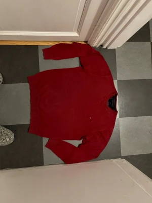 Röd tröja Tommy Hilfiger M - Säljer en klassisk röd tröja från Tommy Hilfiger i storlek M. Tröjan är gjord i 100% bomull och har rund halsringning samt ribbade muddar vid ärmslut och nederkant. Perfekt för dig som gillar stilrena och tidlösa plagg.