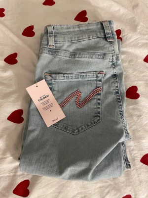 Ljusblå bootcut jeans från Nelly - säljer dessa snygga ljusblå jeans från Nelly, då jag råkade beställa två så dom är helt oanvända! Dem har låg midja och bootcut-ben. Jeansen har slitna detaljer vid knäna och en cool rosa broderad zigzag på bakfickan.🔥