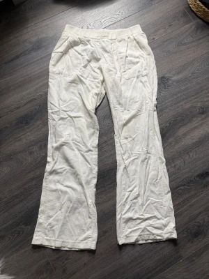 Vita linnebyxor med raka ben - Säljer ett par vita linnebyxor med resår i midjan och raka ben. Byxorna har sidfickor och en enkel, avslappnad look. Perfekta för varma dagar och ger en chill vibe till outfiten.