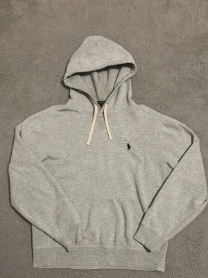 Grå Ralph lauren hoodie - Säljer denna riktigt feta hoodie från Polo Ralph Lauren med klassiskt logga på bröstet. Storlek S, passar om du är 170-180 cm.