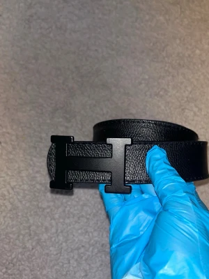 Svart skärp med H-spänne - Snyggt svart skärp med ett stort H-format spänne i matt svart finish. Skärpet är gjort i präglat skinn och har en stilren, klassisk look som passar till jeans eller kostymbyxor. Perfekt accessoar för att lyfta din outfit. Den är förstörd bakom men annars är den bra. Aktiv 24/7✅ Skickar direkt eller dagen efter📦Hör av dig via frågor⁉️🙋‍♂️