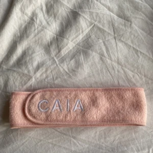 Rosa sminkband från CAIA - Snyggt rosa sminkband från CAIA med broderad logga i vitt. Inga fläckar men lite ludd på ena kardborre bandet. Annars  Som nytt✨