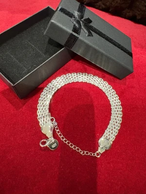 Silver armband 925 bred länkväst - Snygg och bred silverfärgad länkväst med justerbar kedja och karbinlås. Västen har en glansig finish och är tillverkad i 925 sterling silver, vilket syns på den lilla brickan vid låset. Perfekt för att ge din outfit en cool edge.