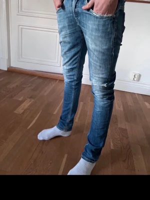 Dondup George  - Säljer ett par Dondup George jeans i blå tvätt med skinny passform. Jeansen har klassiska fem fickor, slitningar vid knäna och snygga detaljer på bakfickorna. Dem är riktigt sköna med lite stretch som ger den perfekta passformen🫰🏻 Modellen är 175 cm, 55kg