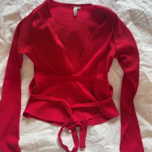 Röd Nelly topp - Snygg röd omlottopp med långa ärmar och knytband i midjan från Nelly. Strl xxs använd en gång