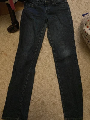 Esprit Star Slim mörkblå jeans 28/32 - Mörkblå jeans från Esprit Casual Denim i modellen Star Slim. Klassisk femficksdesign med knapp och dragkedja fram. Slim fit och raka ben, perfekt för dig som gillar en stilren look. Materialet är slitstarkt jeans och färgen är djupblå.