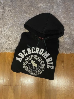 Svart Abercrombie hoodie - Hej! Säljer en svart Abercrombie hoodie I storleken M. Hoodien är i jättebra skick. Lite luddig på bokstäverna. Hör gärna av er vid frågor.