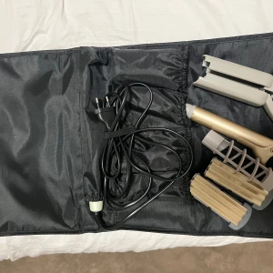 Philips stylingverktyg med väska - Säljer ett Philips stylingverktyg med flera utbytbara plattor och tillbehör, perfekt för att skapa olika frisyrer. Kommer med en svart förvaringsväska med Philips-logga. Verktyget har en guldig och grå finish och är elektriskt med sladd.