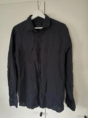 Riley linneskjorta svart - Svart ursnygg populär och trendig Riley linne skjorta i storlek M. Superfint skick då den är använd mycket sparsamt och perfekt till alla möjliga tillfällen! Inga defekter, pris ej hugget i sten och tveka inte vid minsta fråga eller fundering!