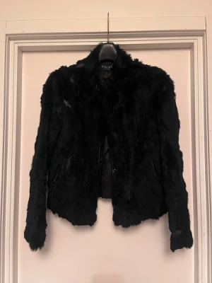 Svart kaninpäls från Hollies - Hollies kaninpäls. Älskad och använd. Mycket varm och skön. Storlek 40, använd som oversize då jag själv har 34 i storlek. Svart.  Upplagd på flera säljsidor, först till kvarn.