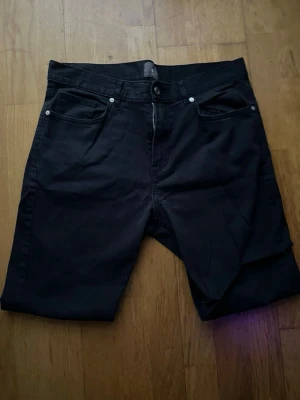 Mörklblå chinos med fem fickor - Säljer ett par svarta shorts med klassisk femficksdesign och knapp samt dragkedja framtill. De har raka ben och är tillverkade i ett mjukt bomullsmaterial som är skönt att bära. Perfekta för dig som gillar enkel och stilren look. Skriv för mer bilder eller frågor