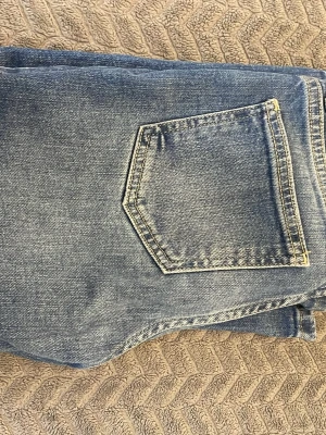 Blå bootcut jeans från Levi's - Säljer ett par klassiska blå Levi's jeans med bootcut passform. Jeansen har en snygg tvätt med ljusare partier och tydliga sömmar runt bakfickan. Materialet är slitstarkt jeans och modellen har en rak, något utsvängd benform.