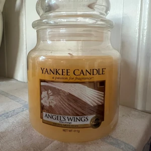 Yankee Candle Angel’s Wings - Aldrig använt Yankee Candle Angel's Wings doftljus i glasburk. Missfärgning på baksidan, se bild.