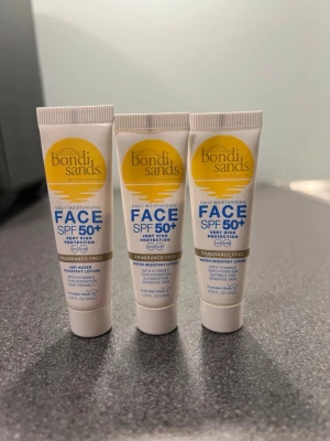 Bondi Sands Face SPF 50+  - Bondi Sands The Australian tan Daily Moisturising Face SPF 50+, parfymfri och vattenresistent med vitamin E. Ger 72 timmars återfuktning och passar känslig hud. Tuben är vit med gul och blå text, innehåller 10 ml vardera. Säljer alla tre för 11kr. Helt oanvända