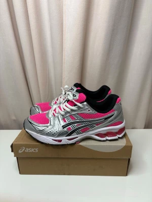 ASICS Gel-Kayano 14 rosa/silver sneakers - Säljer ett par ASICS Gel-Kayano 14 sneakers i en riktigt fet färgkombo med rosa mesh, silverdetaljer och svarta inslag. Skorna har vit sula med rosa detaljer och klassisk snörning. Perfekta för dig som vill sticka ut och köra på en sportig vibe.