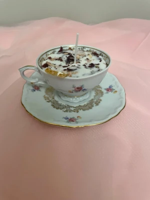 Doftljus i en vit tekopp med blommor i doft utav vanilj - Det här ljuset är gjort av återanvändbara material. Tekoppen är köpt secondhand och stearinet är från kyrkor som tänkte slänga det. Det här ljuset har en svag doft utav vanilj, så känsliga även kan använda det. Det här ljuset har även torkade blommor och torkad apelsin på som dekoration. Det finns fler av denna design på hemsidan om man vill köpa sets. 