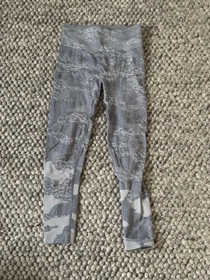 Grå-blå camo leggings från Gymshark - Säljer ett par grå-blå leggings från Gymshark med camouflagemönster. De är högmidjade och har en tight passform som sitter snyggt på kroppen. Perfekta för träning eller chill. Materialet är stretchigt och andas bra.