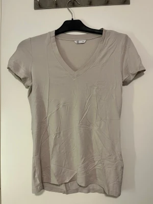 Beige v-ringad t-shirt från Cubus - En enkel och stilren beige t-shirt från Cubus i storlek XS. T-shirten har v-ringning och korta ärmar, perfekt för en clean och avslappnad look. Tillverkad i mjuk bomull som känns skön mot huden. Har aldrig använts. Pris kan alltid diskuteras!🤗