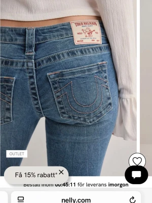 Blå True Religion bootcut jeans - Säljer ett par ljusblå jeans från True Religion med rosa sömmar. låg midja och bootcut. Tillverkade i mjukt jeansmaterial. De är i bra skick men kan inte ha de för att de är för korta på mig❤️