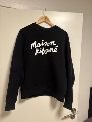 Maison Kitsuné svart sweatshirt - Svart sweatshirt från Maison Kitsuné med vit logotyp framtill. Klassisk rund halsringning och långa ärmar. Kvitto och äkthetsbevis finns