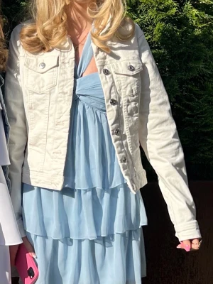 Vit jeansjacka med silverknappar - Säljer en fräsch vit jeansjacka från Only med klassisk krage, långa ärmar och snygga silverfärgade knappar framtill. Jackan har två bröstfickor med lock och knapp samt en croppad passform som ger en trendig look.