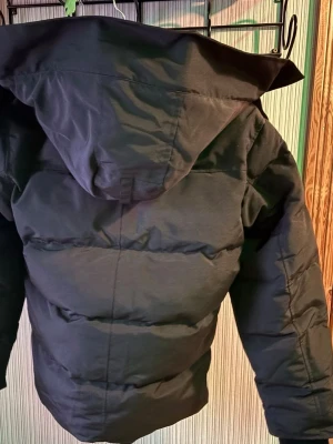 Canada Goose Wyndham, OANVÄNT - Säljer en svart pufferjacka från Canada Goose, Wyndham black med black badge. Jackan har knappar och dragkedja framtill samt två stora fickor. Materialet är topp klass, perfekt för kalla och vindiga dagar. Klassisk stil med en svart logga på armen, allt ingår med jackan är hel svart och kommer med pälset och den är ner packad i originala påsen den kom i, HELT NYTT OANVÄNT. PRISET KAN DISKUTERAS UNDER SNABB AFFÄR