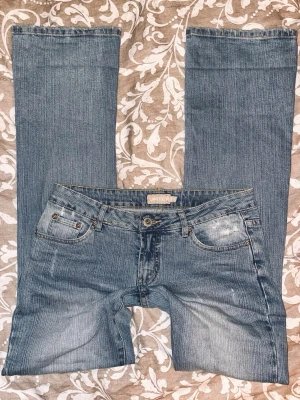 Lågmidjade jeans - Säljer ett par äkta snygga vintage jeans🤩de är bootcut, ljusblå och har gulliga detaljer på bakfickorna! De har en nästan osynlig gul fläck på ena låret som syns på sista bilden, men annars är de i bra kvalitet!  Passar S - M.     Midjemått: 37cm rakt över.  Innerbenslängd: 86 cm