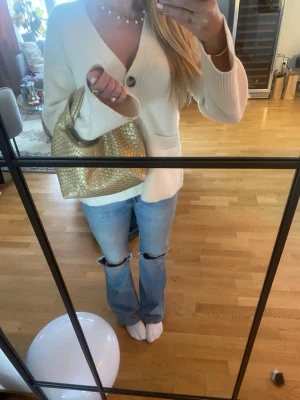 Guldig axelväska i flätad skinnimitation - Säljer en superfin axelväska i guld med flätad struktur. Väskan har en mjuk, rundad form och ett kort handtag som gör den enkel att bära i handen eller över armen. Perfekt för dig som vill addera lite extra bling till din outfit.