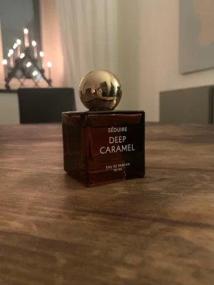 SÉDUIRE Deep Caramel parfym - Eau de Parfum från Seduire med namnet Deep Caramel, 50 ml. Se bild för hur mycket det finns kvar i flaskan. Har tyvärr ingen tillhörande låda kvar. Nypris: 899:-