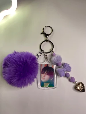 Nyckelring Stray kids - Nyckelring stray kids lila.   Vad som ingår- En bild på stray kids medlem En fluffig lila boll En accessoar med hjärta som går att öppna  En Karbinhake