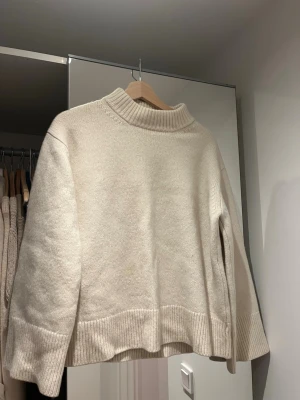 Beige stickad tröja Nathalie Schuterman - Säljer en beige stickad tröja från Nathalie Schuterman. Tröjan har en hög ribbad krage, breda muddar och lång ärm. Passformen är loose och materialet känns mjukt och lyxigt, perfekt för kyliga dagar. Några små "fläckar" som ej syns se bilder. Storlek M/L men skulle söga snarare en S. Nypris 14 000kr.