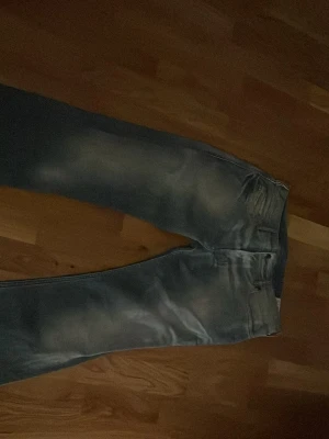 Blå bootcut jeans från Diesel - Säljer ett par ljusblå bootcut jeans från Diesel med snygg slitning och klassiska bakfickor med V-detalj. Jeansen har normal passform och är tillverkade i mjukt denimtyg. Perfekta för dig som gillar retrovibbar och vill ha ett par riktigt schyssta jeans.