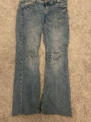 Blå bootcut jeans med broderad ficka - Säljer ett par blåa jeans från HM som inte säljs längre! Är i fint skick dock har det kommit något blått runt ena hålet( se bild 4) där efter är då priset 120 kr men kan diskuteras 