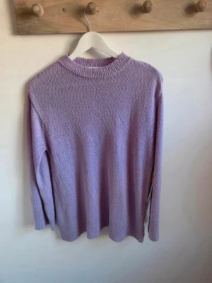 Ljuslila stickad tröja Stories S - Supersöt ljuslila stickad tröja från Stories i storlek S. Tröjan har en ribbad rund halsringning och långa ärmar. Perfekt till både jeans och kjol för en chill och trendig look. Materialet är mjukt och ger en mysig känsla.