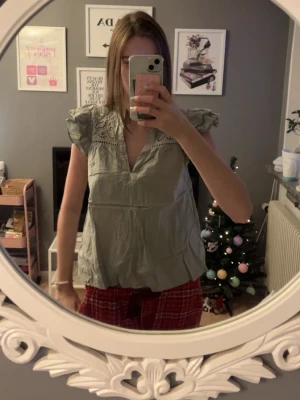 Ljusgrön blus med spetsdetaljer - Säljer en ljusgrön blus med volangärmar och v-ringning. Blusen har fina spetsdetaljer. Perfekt för dig som gillar romantiska och luftiga plagg.