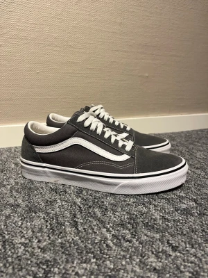 Gråa Vans Old Skool sneakers - Säljer ett par klassiska Vans Old Skool sneakers i grått med vit sula och vit sidostripes. Perfekt skick