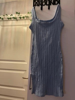 Ljusblå ribbad kortklänning - Supersöt ljusblå kortklänning med ribbad struktur och ärmlös design. Klänningen har en rundad halsringning och sitter figurnära. Perfekt för dig som vill ha en enkel men snygg look till sommaren.