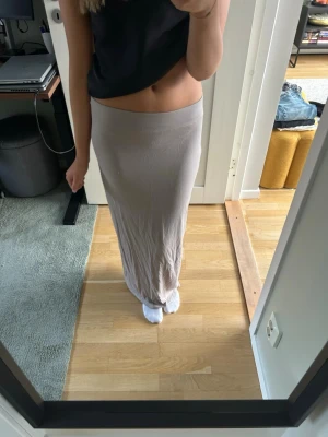Beige långkjol från 157 - Säljer en enkel och stilren beige långkjol från 157. Kjolen har en rak passform och är gjord i ett mjukt och stretchigt material som sitter skönt i midjan. Perfekt att matcha med crop tops eller stickade tröjor.
