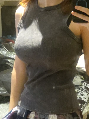 Mörkgrå ribbad linnetopp - Säljer en mörkgrå ribbad linnetopp med hög hals och ärmlös design. Toppen har en tight passform och är tillverkad i ett mjukt, stretchigt material som sitter snyggt på kroppen. Perfekt att styla med jeans eller kjol för en enkel och clean look.