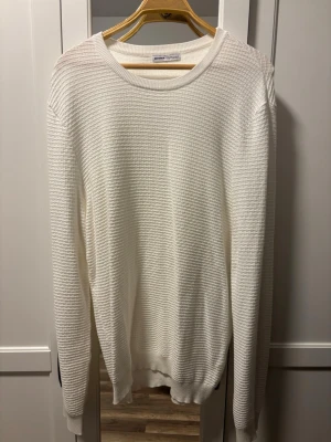 Vit ribbad tröja från Bershka - Säljer en vit långärmad tröja från Bershka i storlek XL. Tröjan har ett ribbat mönster och rund halsringning. Materialet känns mjukt och lätt, perfekt för lager-på-lager under kyliga dagar. Enkel och stilren design som funkar till många olika outfits.