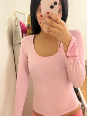 Ljusrosa långärmad topp med slits - Säljer en ljusrosa långärmad topp med rundad urringning från gina