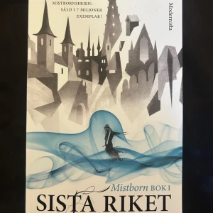 Sista riket (Mistborn Bok 1) - Säljer boken 'Sista riket', första delen i Mistborn-serien av Brandon Sanderson. Omslaget har en fantasifull stad i grå toner och blå rök, med en person i kåpa. Perfekt för dig som gillar episk fantasy och äventyr.