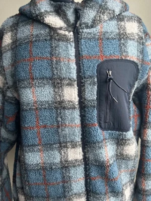 Rutig fleecejacka från JW Anderson x Uniqlo - Säljer en rutig teddyjacka med huva från JW Anderson x Uniqlo. Jackan är blå, grå och vit med orange detaljer, har en praktisk bröstficka med dragkedja och är tillverkad i mjuk fleece. Perfekt för kyliga dagar och har en avslappnad passform.