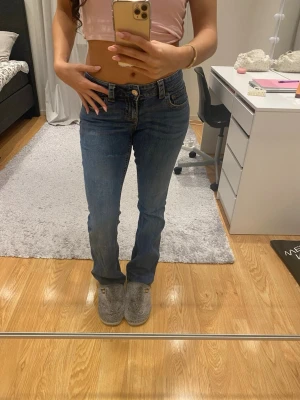  Blå bootcut jeans - Säljer ett par klassiska blå jeans med bootcut passform och låg midja. Jeansen har fem fickor, knapp och dragkedja framtill. Perfekta för dig som gillar en tidlös och avslappnad stil.