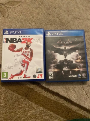 PS4 Spel: NBA 2K21 & Batman Arkham Knight - Två PS4-spel i bra skick: NBA 2K21 (basketspel med Lillard på omslaget) och Batman Arkham Knight (actionäventyr i Gotham). Omslagen och fodralen ser hela ut, inga synliga skador.