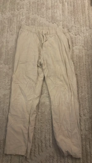 BEIGE LINNE BYXOR  - Beige linnebyxor HM storlek S Regular. Defekter finns på bakre höger ben, finns bilder. Inte använt så många gånger.