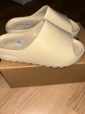Adidas Yeezy Slide i beige - Helt nya allt originalt finns kvar. Kan mötas i Stockholm eller frakt STORLEK 44.5