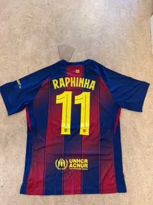 Barça matchtröja Raphinha 11 Nike - Säljer en FC Barcelona matchtröja med Raphinha 11 på ryggen. Tröjan är randig i marinblått och vinrött med gula detaljer, Nike-logga och Spotify sponsor på bröstet. Tillverkad i lätt polyester med Dri-Fit ADV-teknologi för extra komfort.
